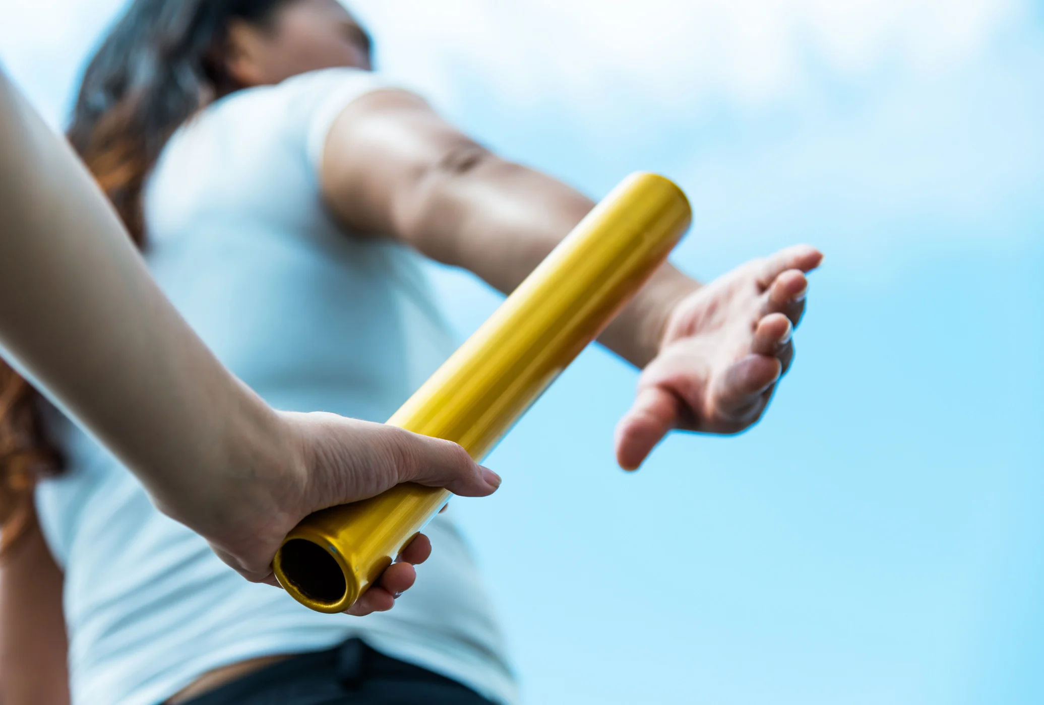 Two hands passing the baton for a relay race